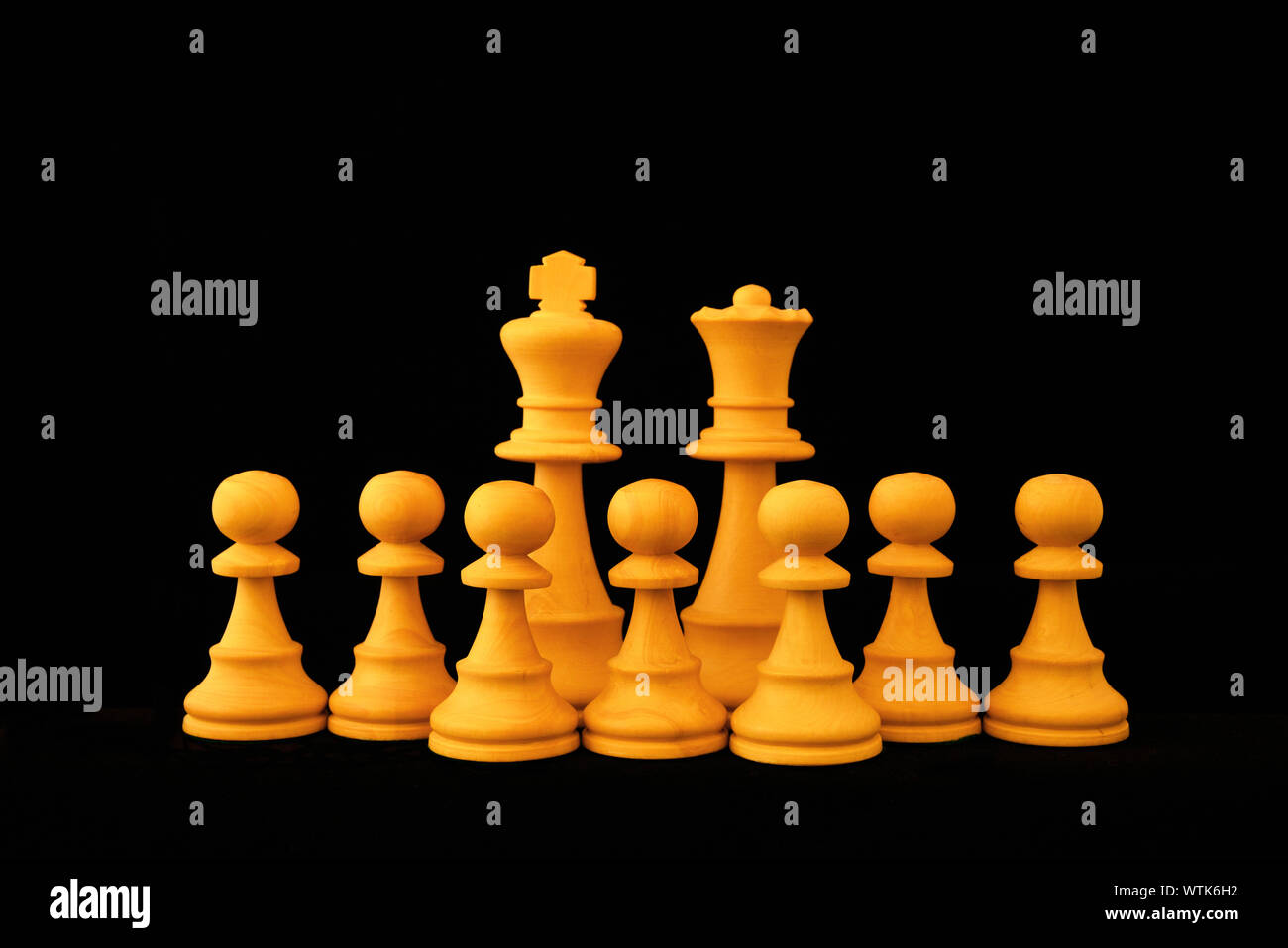 Re bianco, la Regina e il pedone numeorus come grande famiglia e concetto di fertilità. Standard del gioco degli scacchi pezzi di legno su sfondo nero Foto Stock