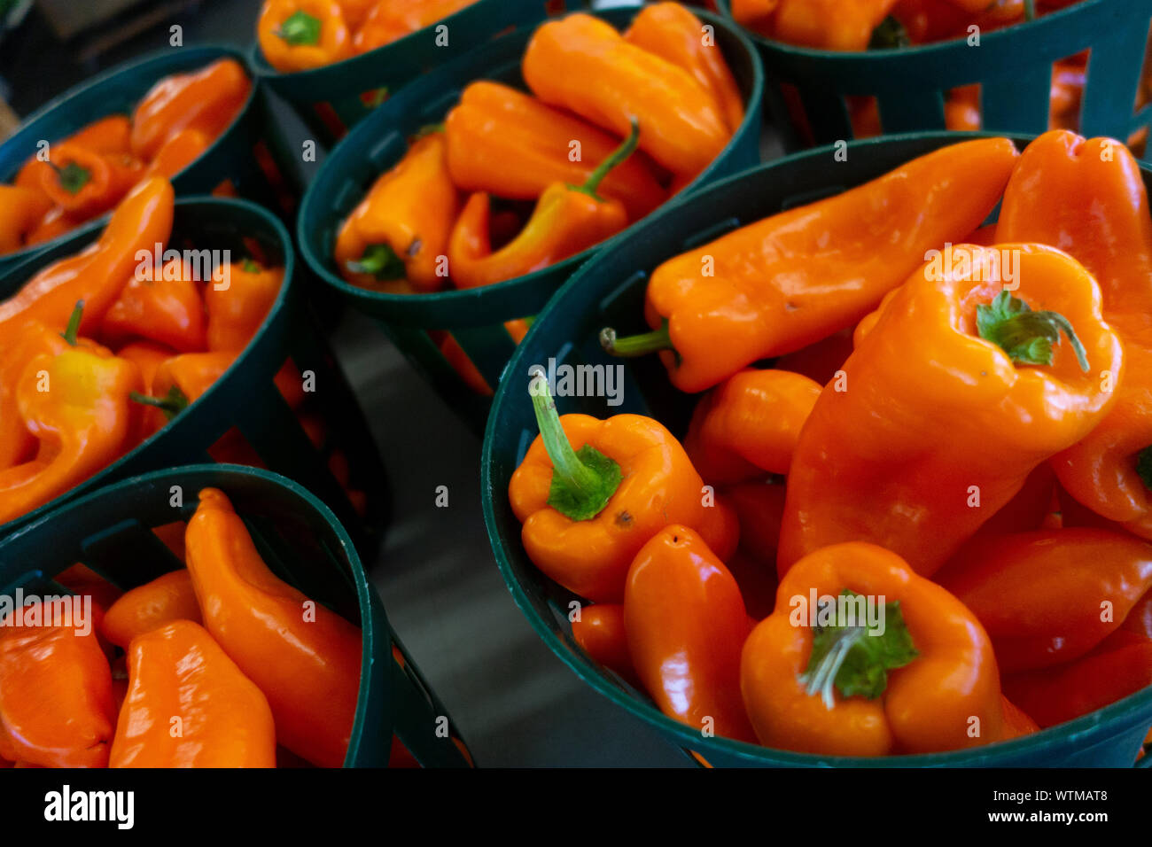 Peperoni arancioni in cesti in vendita presso un mercato agricolo locale Foto Stock