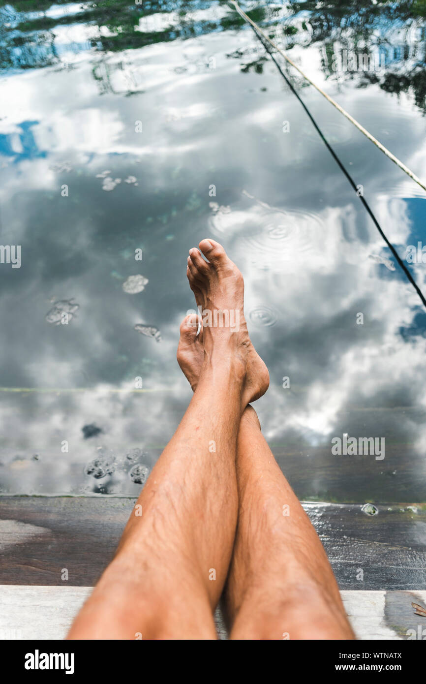 Ritagliare le gambe dei piedi nudi di sesso maschile di prendere il sole in relax Cenote Crystal Foto Stock