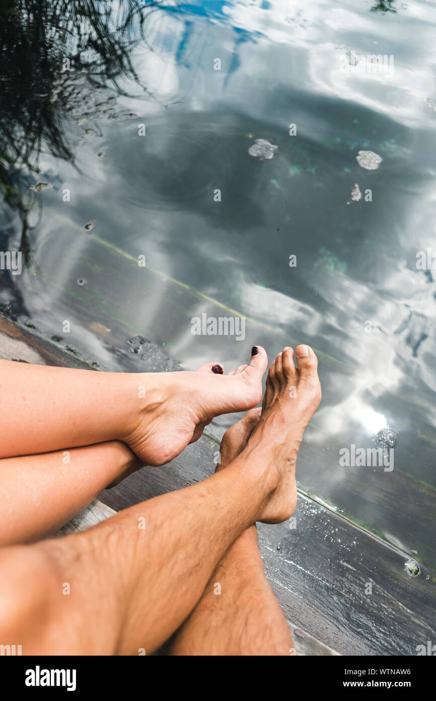 Gambe di anonimo a piedi nudi giovane sulla superficie tranquilla del Cenote Foto Stock