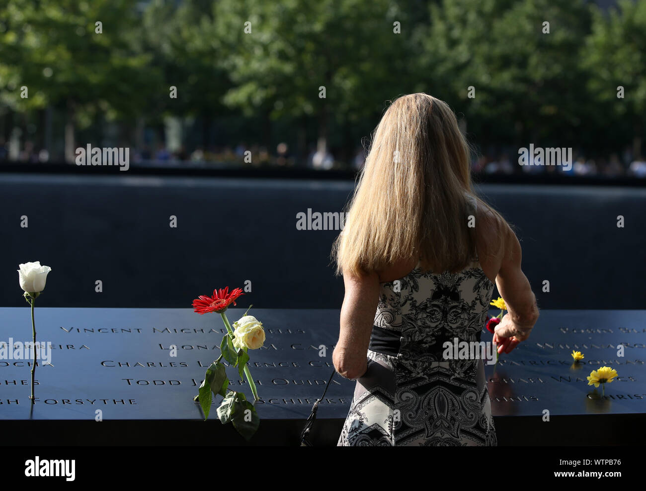 New York, Stati Uniti d'America. Undicesimo Sep, 2019. Una donna mette fiori a piangere le vittime degli attacchi terroristici dell 11 settembre presso il National September 11 Memorial Museum di New York, Stati Uniti, Sett. 11, 2019. Persone hanno pagato la loro omaggi qui il mercoledì a piangere le vittime degli attacchi terroristici dell 11 settembre che è accaduto 18 anni fa e rivendicato il sacrificio di migliaia di vite umane. Credito: Qin Lang/Xinhua/Alamy Live News Foto Stock