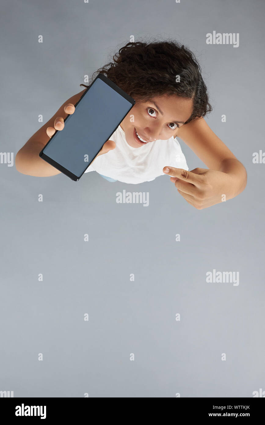 Giovane donna punto il dito sulla schermata dello smartphone al di sopra vista dall'alto di sfondo per studio Foto Stock