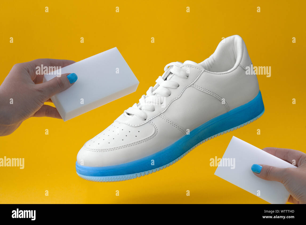 Alla moda sneakers Bianco con suola blu e mani femminili con spugne su sfondo giallo scarpe concetto di cura Foto stock Alamy