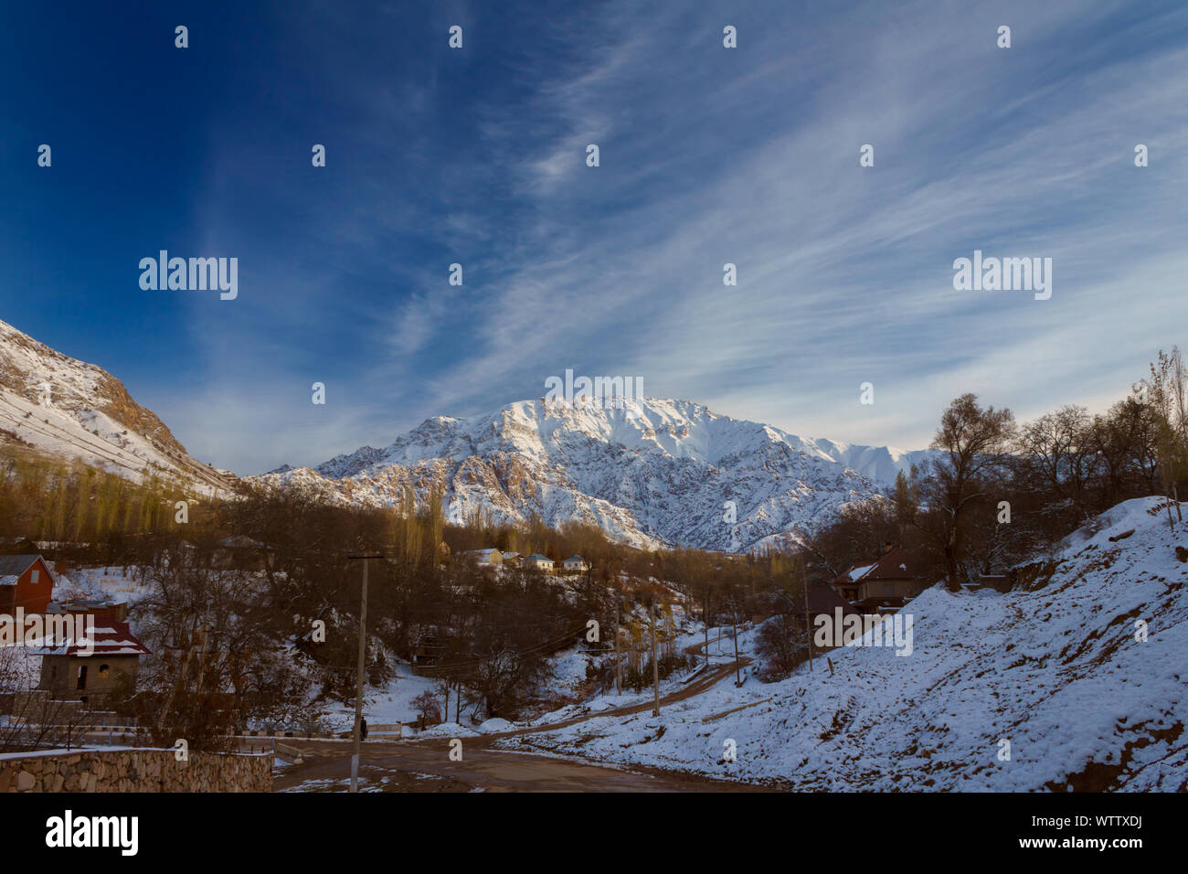 Alpi montagna parzialmente coperto di neve sopra piccolo villaggio, tardo autunno Foto Stock