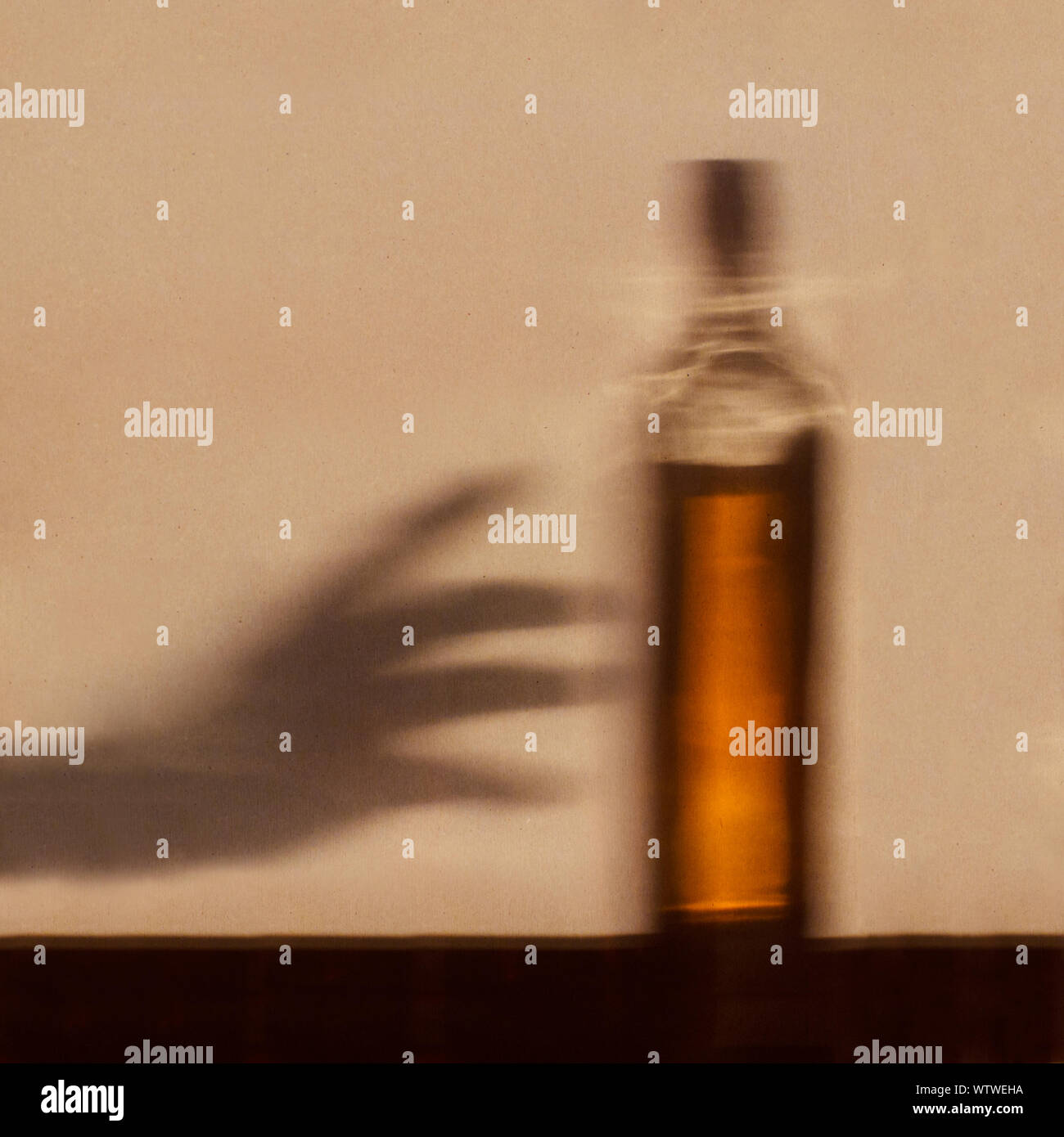 Alcool dipendenza concetto - Ombra di mano raggiungendo per la bottiglia di alcool Foto Stock