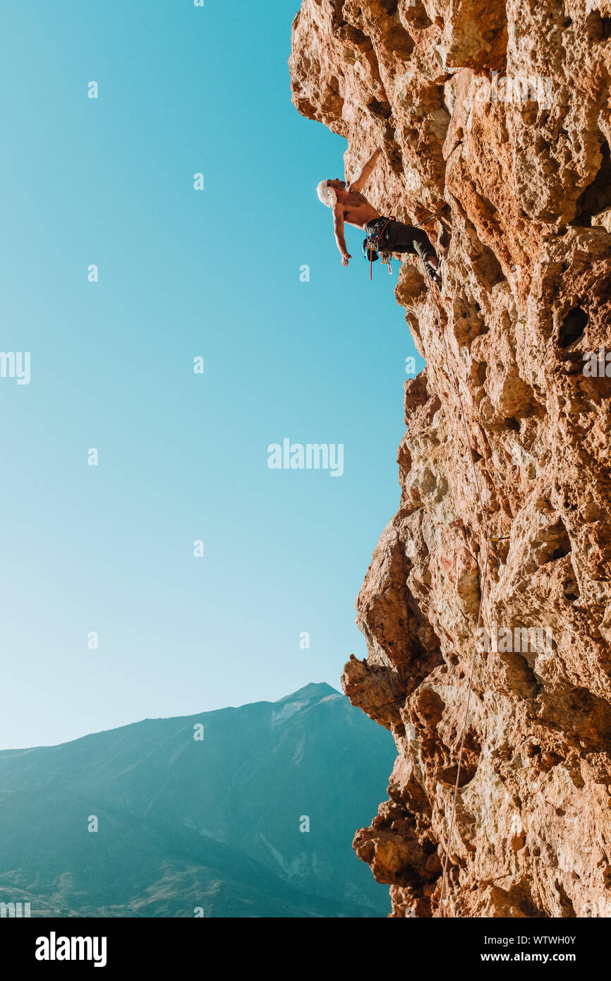 Tirata indietro vista di scalatore maschio sulla parete con El Teide nella parte posteriore Foto Stock