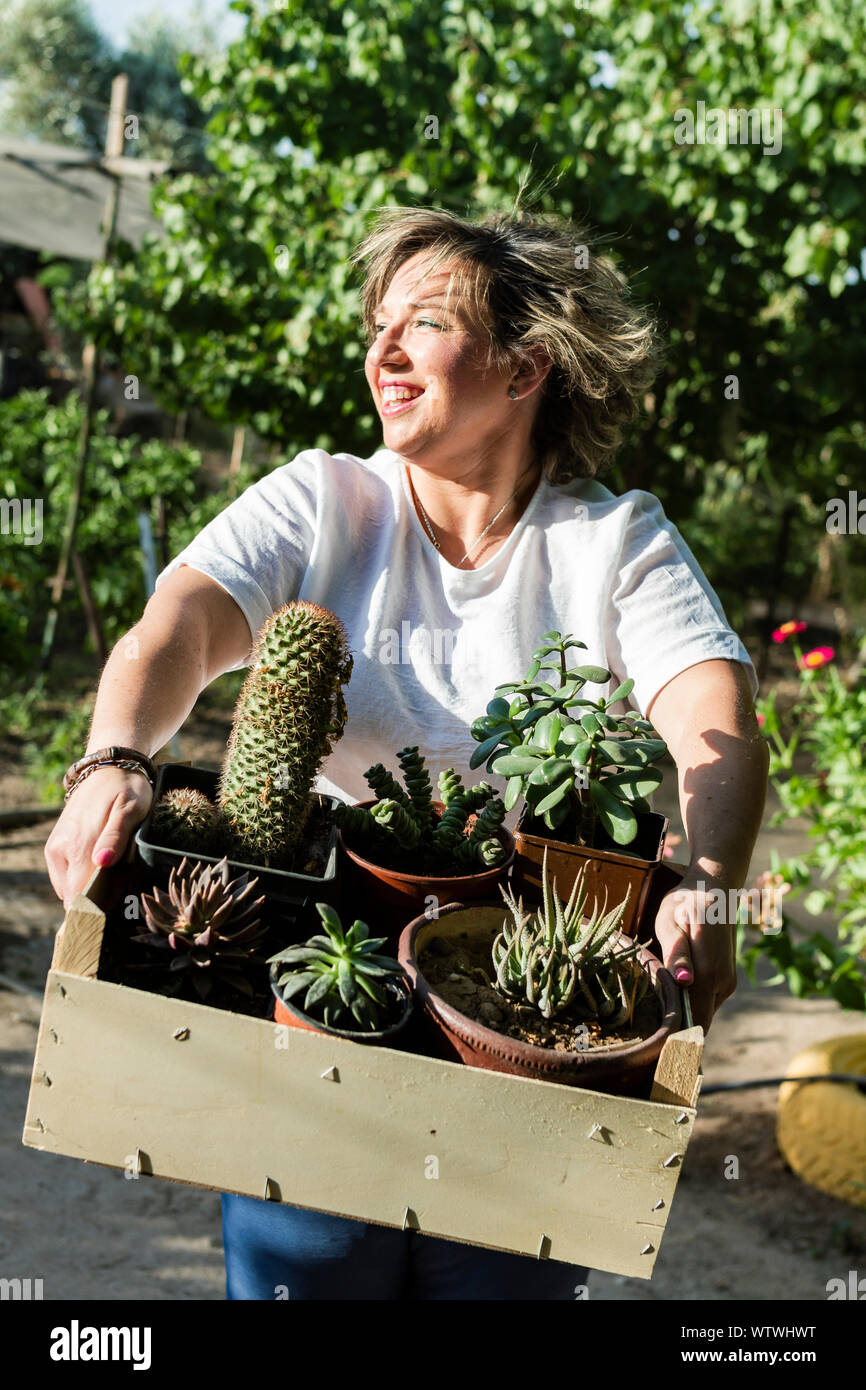 Giovane donna sorrisi come lei si mette in mostra la sua captus e piante su un soleggiato d Foto Stock