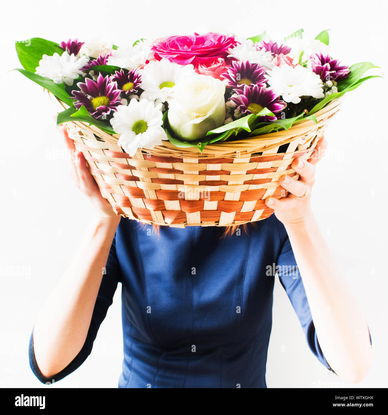 Donna in vestito blu holding cesto in vimini con fiori nelle sue mani  invece di testa. Sfondo isolato. Concetto di vacanza Foto stock - Alamy