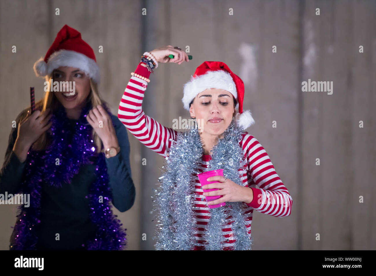 Gruppo multietnico di giovani felici informali di lavoro persone che ballano con botti e divertirsi mentre festeggia capodanno nella parte anteriore della parete di cemento Foto Stock