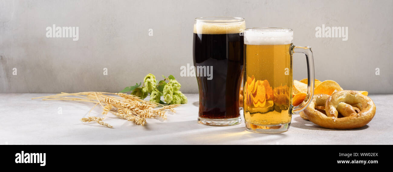 Vari tipi di birra appena spillata - luce e buio e varietà di snack. Gli ingredienti della birra in background. Banner. Copia dello spazio. Foto Stock