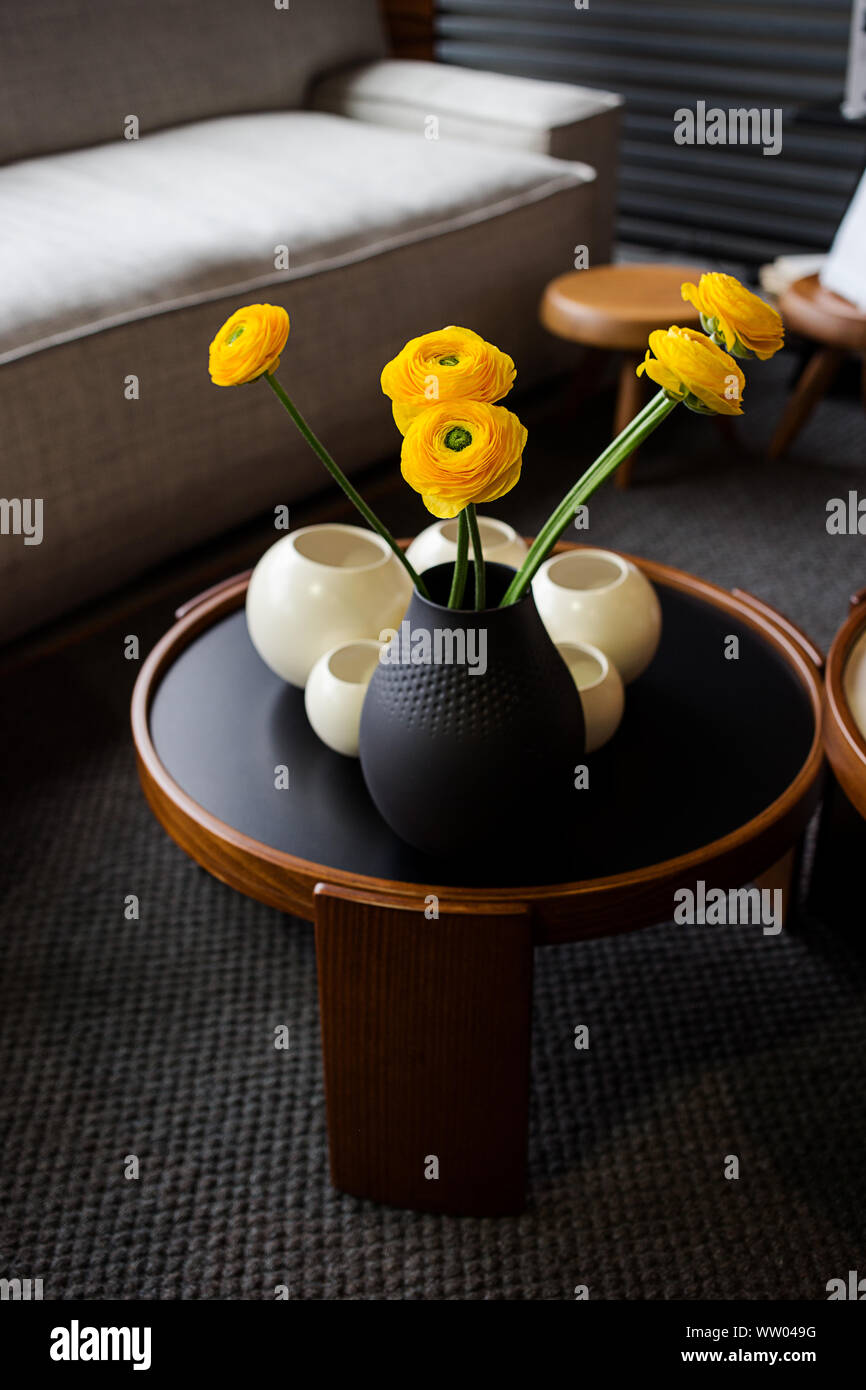 Bouquet di roselline (Ranunculus asiaticus) in un vaso nero. Fiori di colore giallo all'interno. Foto Stock