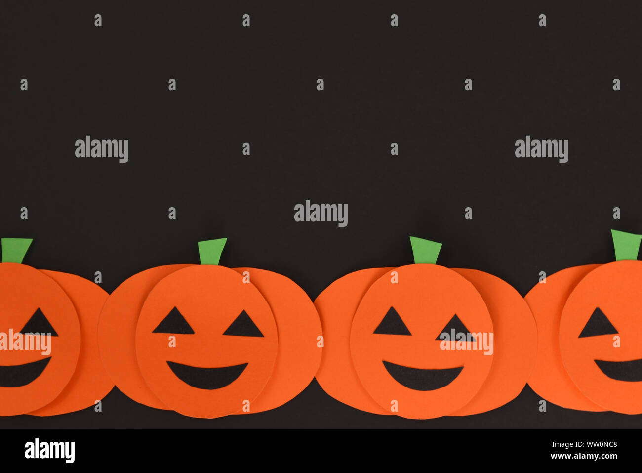 Piatto di Halloween sfondo laici con carta arancione predisposto zucche intagliate con facce su sfondo nero con spazio di copia Foto Stock
