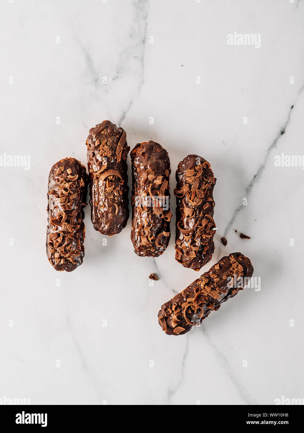 Set di eclairs fatti in casa con cioccolato su sfondo marmo. Vista superiore della deliziosa profitroles sani con glassa di cioccolato. Copia spazio per il testo o il design. In verticale Foto Stock