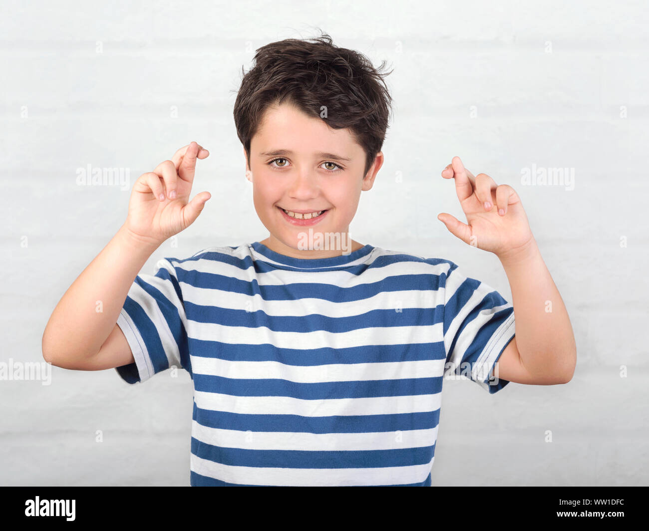 Bambino incrocio le dita le speranze di gud fortuna su Sfondo mattone Foto Stock