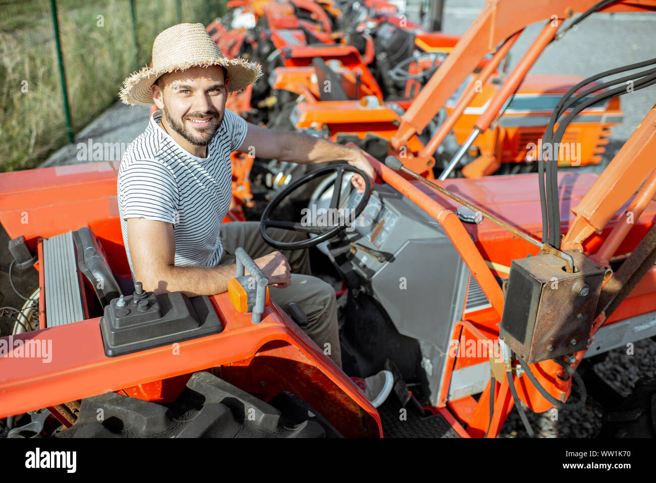 Giovani agronomo cercando il trattore per l'agricoltura, la scelta di macchine agricole sul terreno aperto del negozio Foto Stock