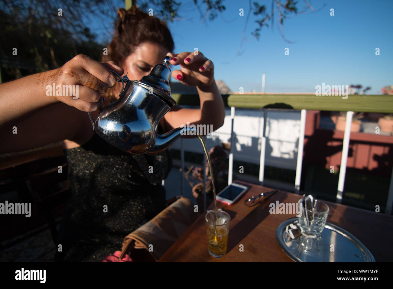 Una donna che serve tè tradizionalmente nella terrazza di un caffè di Marrakesh, Marocco. Foto Stock