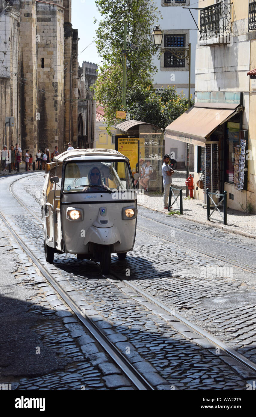 Un tuk tuk guidare su per la strada di ciottoli, Largo da Sé, a Lisbona la città vecchia, il quartiere di Alfama. Il Portogallo fotografie. Foto Stock