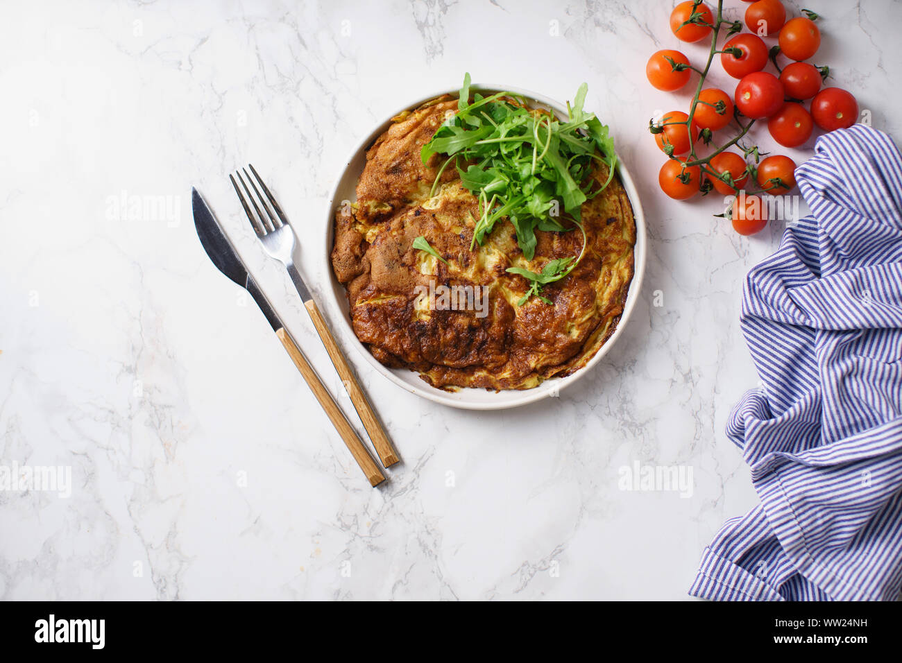 Tortilla frittata con patate tagliate a fette e le erbe sul tavolo di marmo Foto Stock