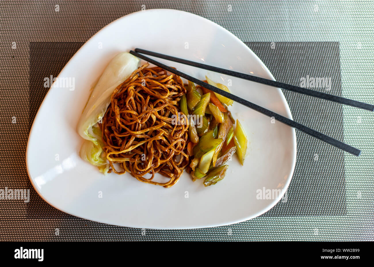 Cinese noodles fritti e bastoncini. Piatto di lato di sedano e le carote. Cavolo cinese. Marrone spaghetti cinesi con verdure. Foto Stock