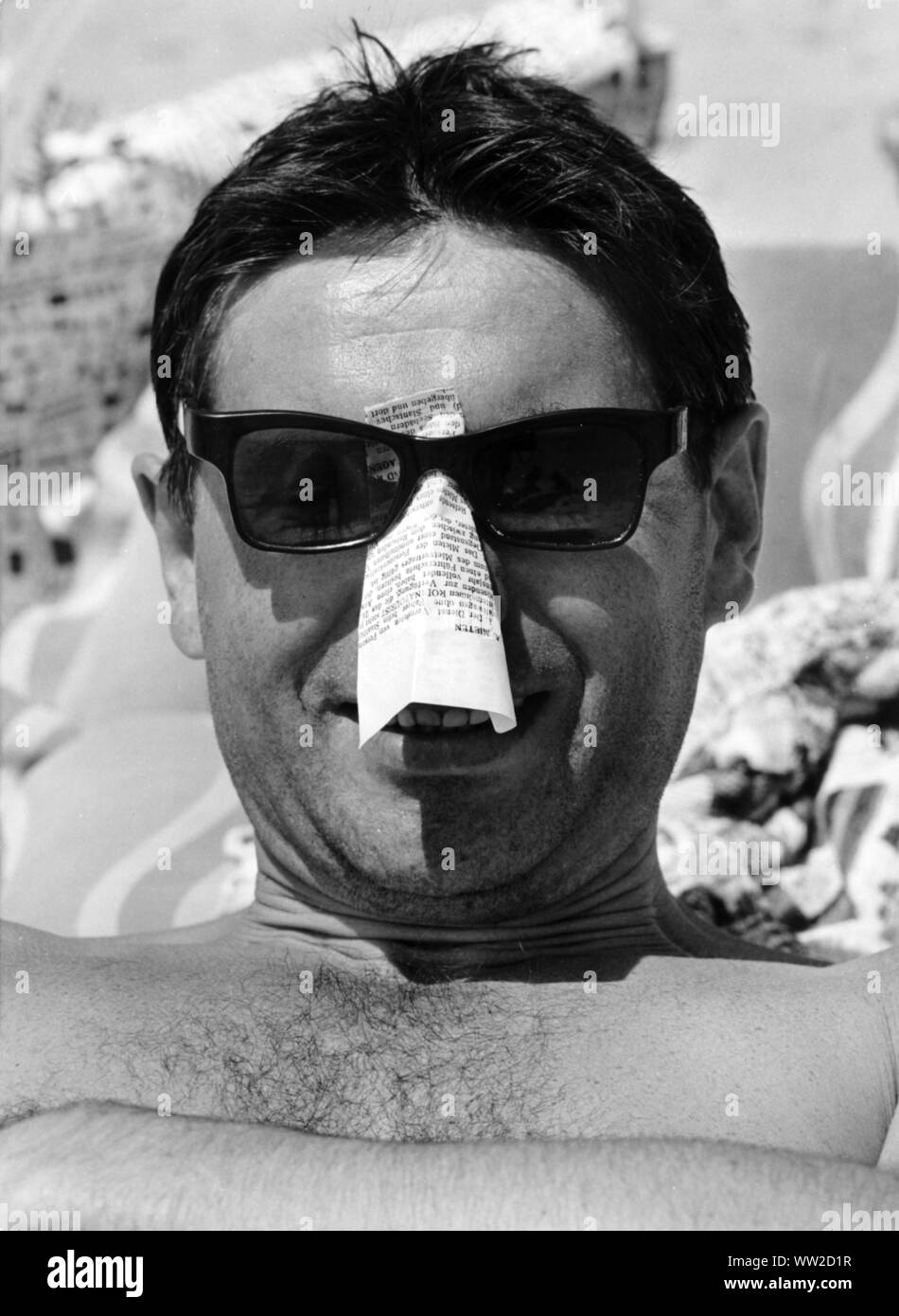 Questo vacanzieri sul Mar Nero in Bulgaria nel luglio 1966 protegge in modo creativo il suo naso da scottature solari: egli ha bloccato un pezzo di carta piegato sotto i suoi occhiali da sole. | Utilizzo di tutto il mondo Foto Stock