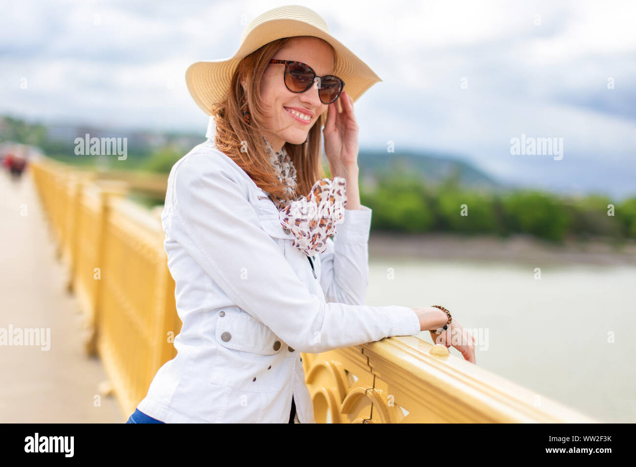Elegante naturale bellezza donna in hat sorridente sul ponte sul Danubio, Ponte Margherita, Budapest, Ungheria Foto Stock