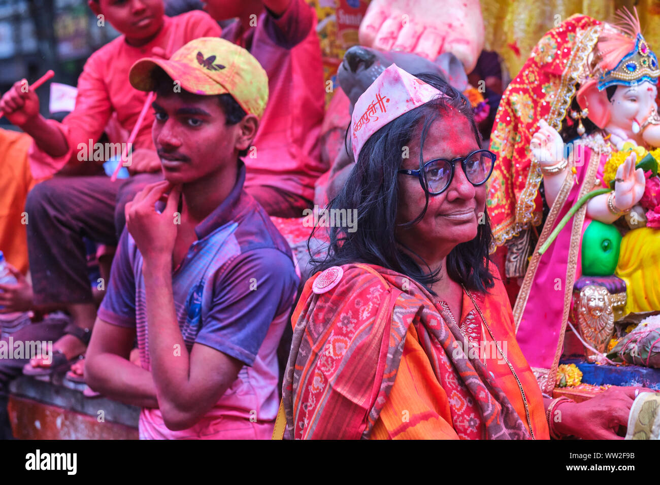 I partecipanti coperto di rosso gulal (gulaal) in polvere, in processione durante il Ganesh Chaturthi (Ganesh Festival) in Mumbai, India Foto Stock