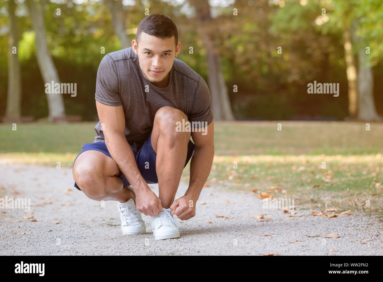 Giovane uomo latino laccio di legatura scarpe passalacci runner pronti la preparazione inizia a correre jogging sport fitness training outdoor Foto Stock