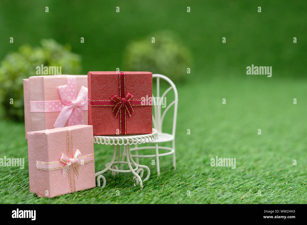 Confezione regalo su campo bianco sedia in giardino verde, con copia spazio per scrivere. Foto Stock