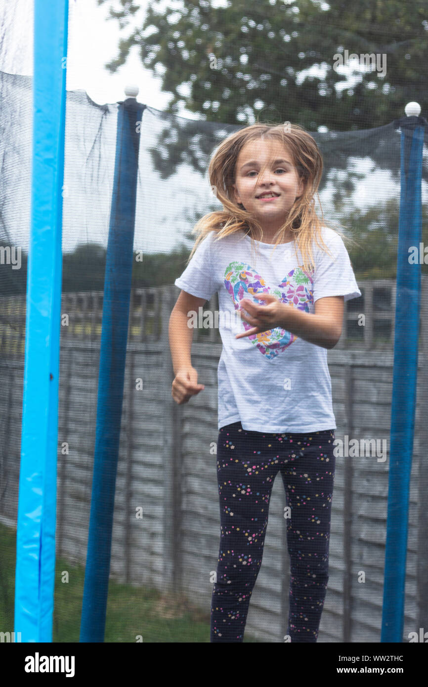 Ragazza che gioca su un trampolino in giardino Foto Stock
