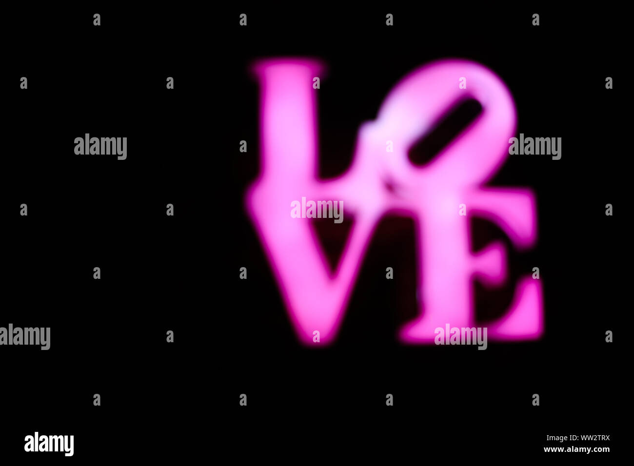 Abstact sfocate rosa in plastica segno della parola amore su sfondo nero. Trendy 80s concetto. Foto Stock
