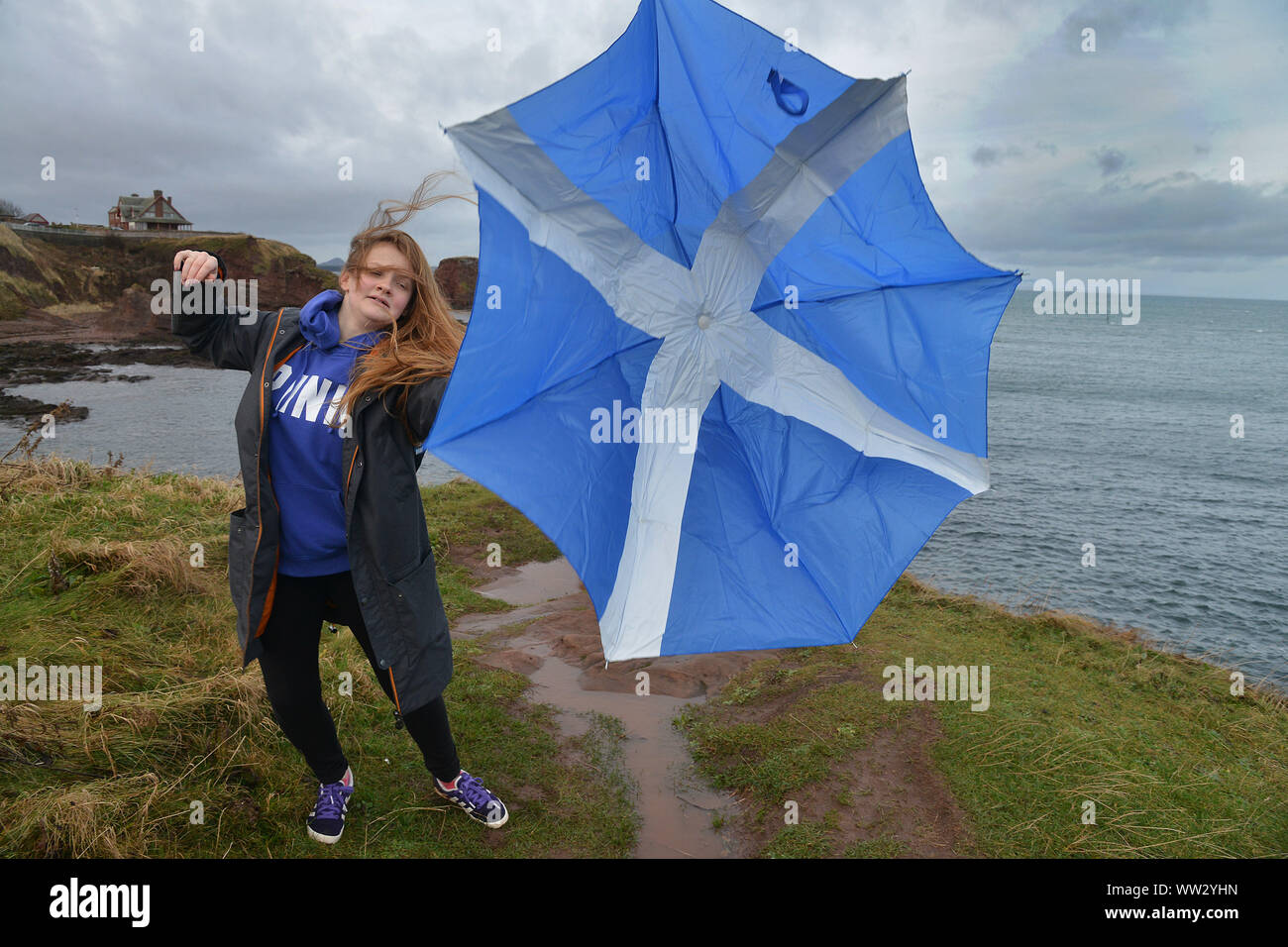 Un viandante battaglie sul bagnato e ventoso a Dunbar, East Lothian, Scozia oggi Foto Stock