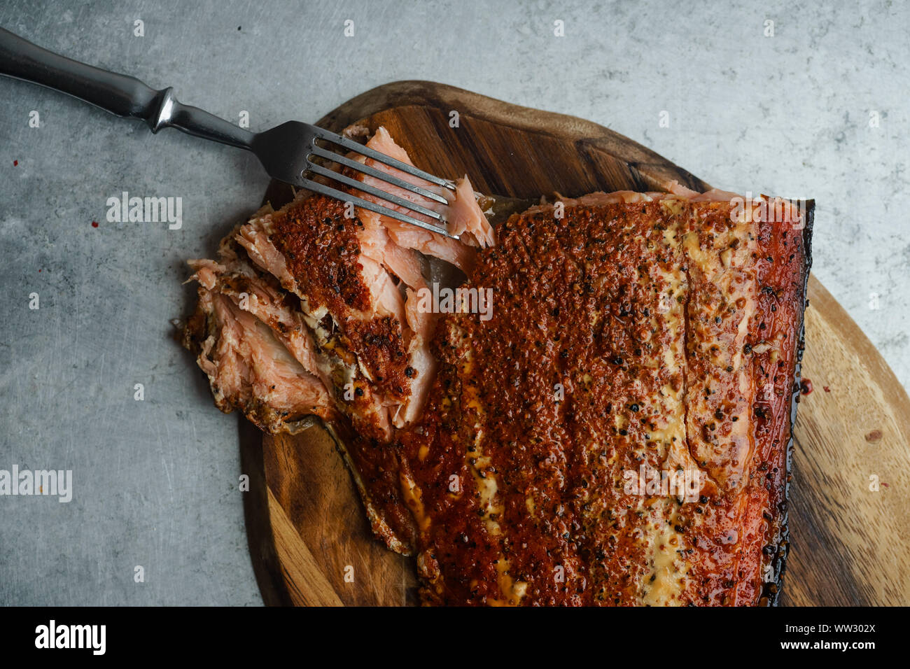 Salmone affumicato con pepe sul tagliere di legno sulla superficie metallica Foto Stock