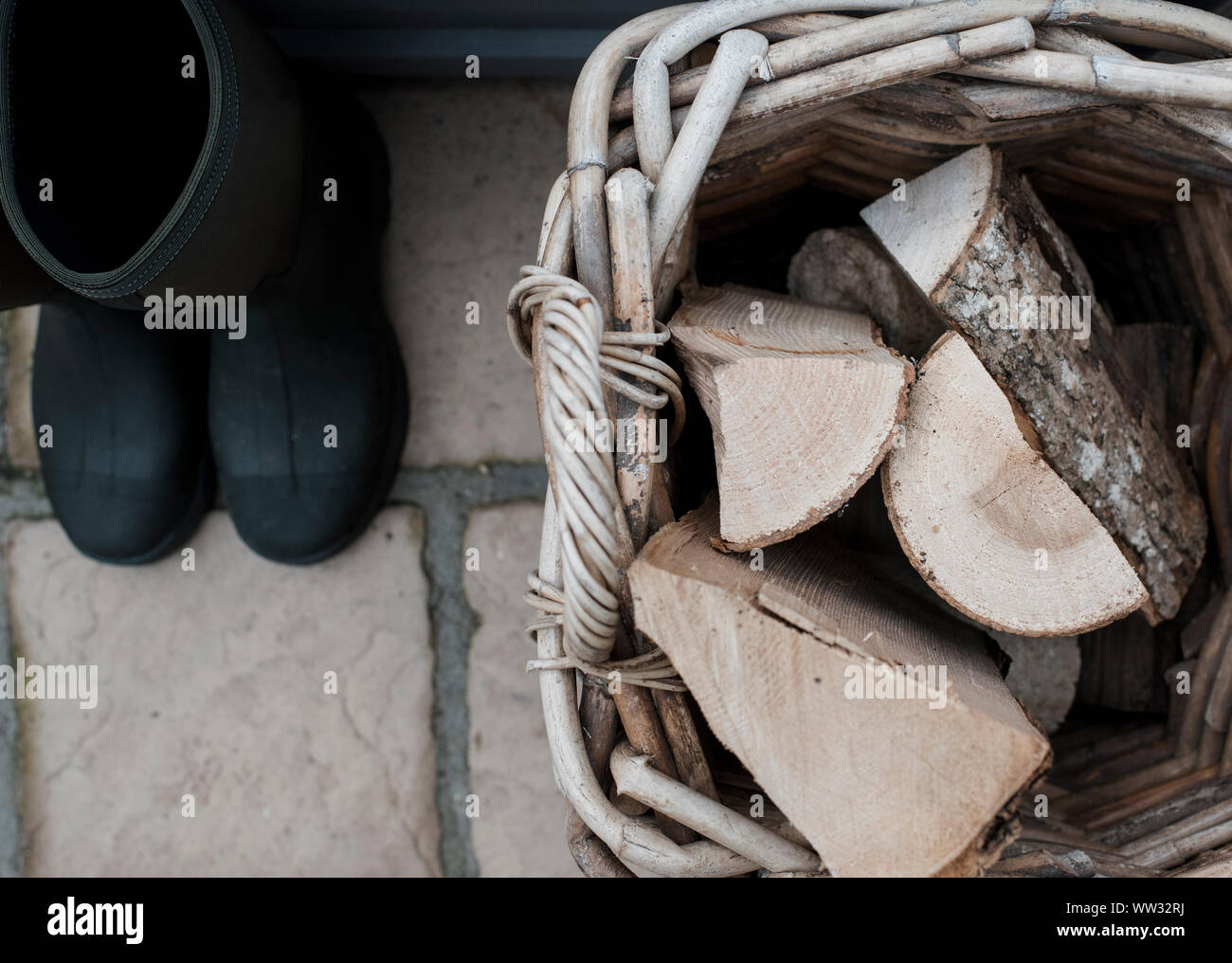 Stivali da pioggia accanto a un cestello di legno tagliato fuori Foto Stock