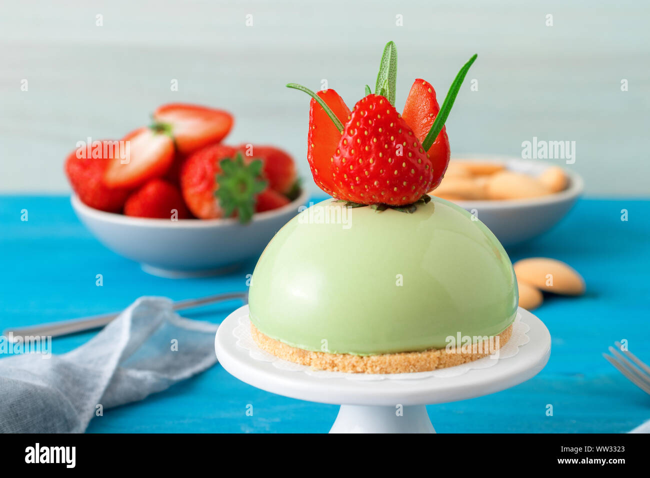 Blue tavolo in legno con no-bake fragola mini sfera matcha cheesecake con coppa di sale caramello, buiscuits e fragole fresche, vetro di piazzole e Foto Stock