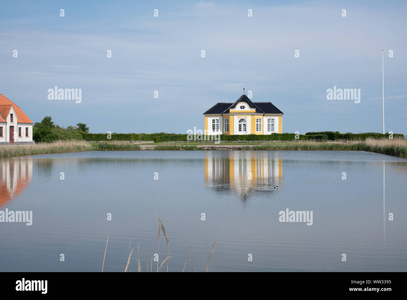 Il giallo garden house al Castello Taasinge, riflettendo in acqua e di Svendborg, Danimarca, 11 Luglio 2019 Foto Stock