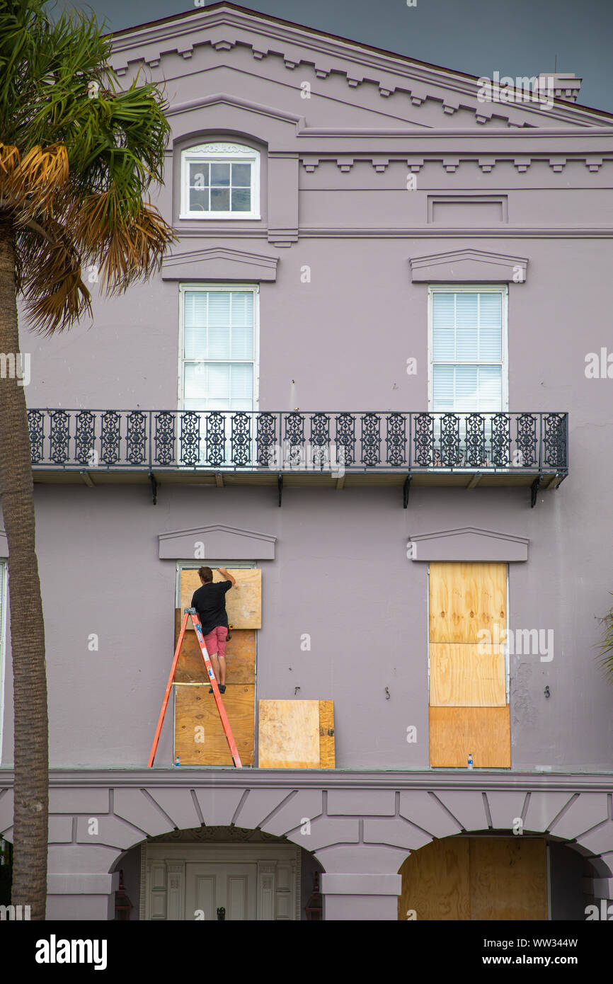 Un lavoratore protegge il legno compensato a windows di una casa storica, Charleston, Sc Foto Stock
