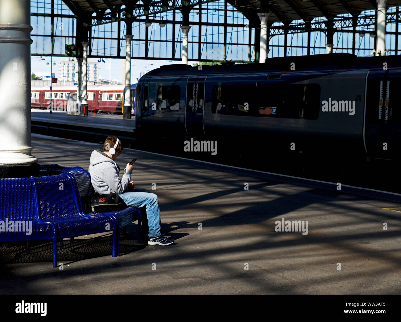 Giovane uomo in attesa di un treno alla stazione ferroviaria, Hull, East Yorkshire, Inghilterra, Regno Unito Foto Stock