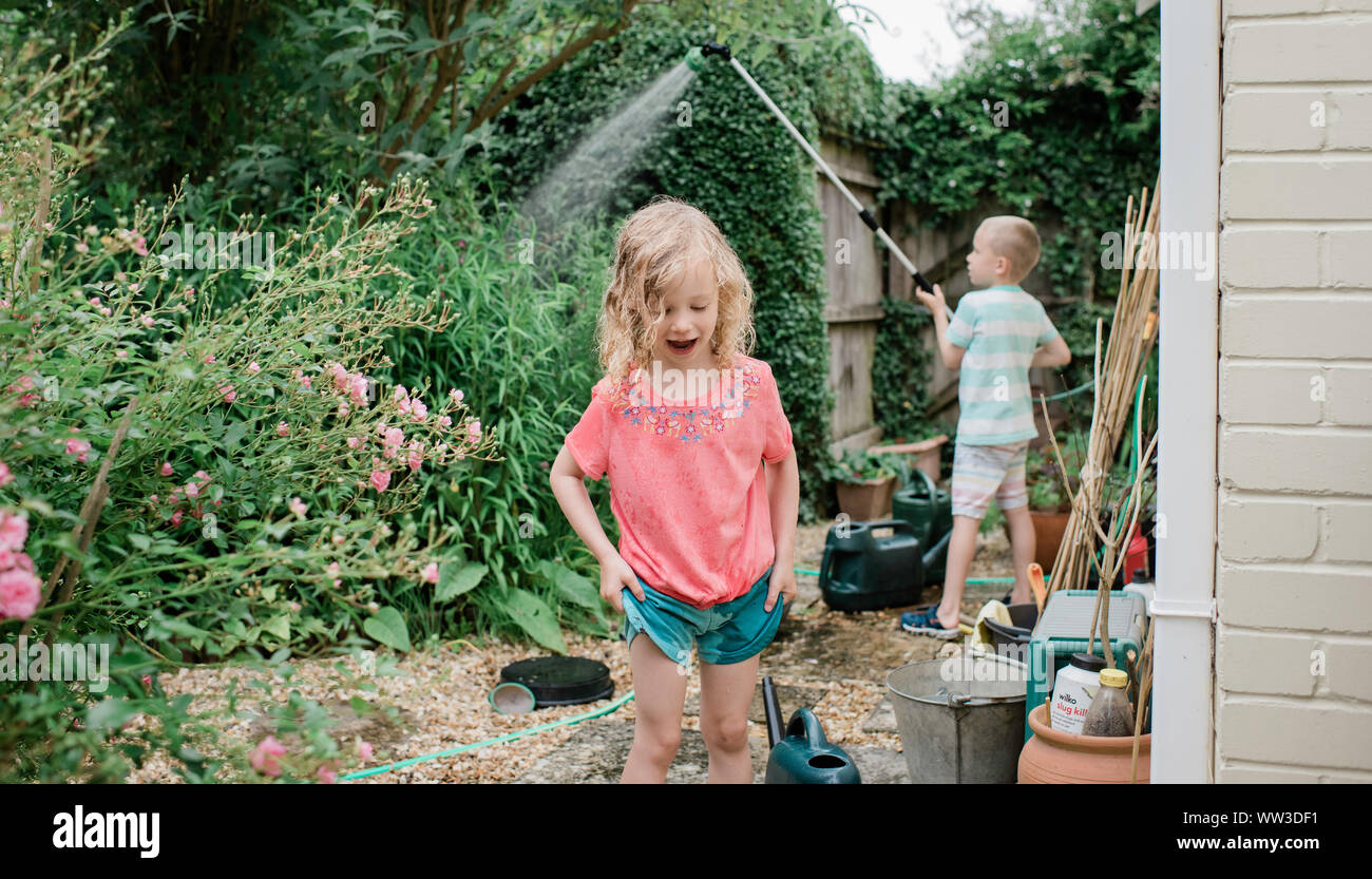 Fratello e Sorella e giocare con l'acqua in un paese di lingua inglese giardino Foto Stock