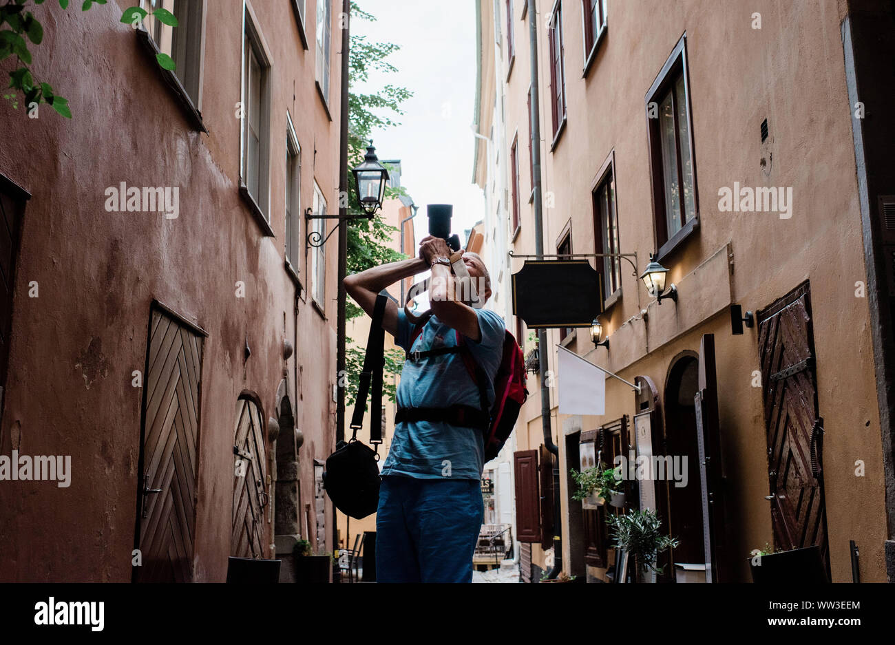Uomo più anziano di scattare foto con una fotocamera reflex digitale di una città come un turista Foto Stock