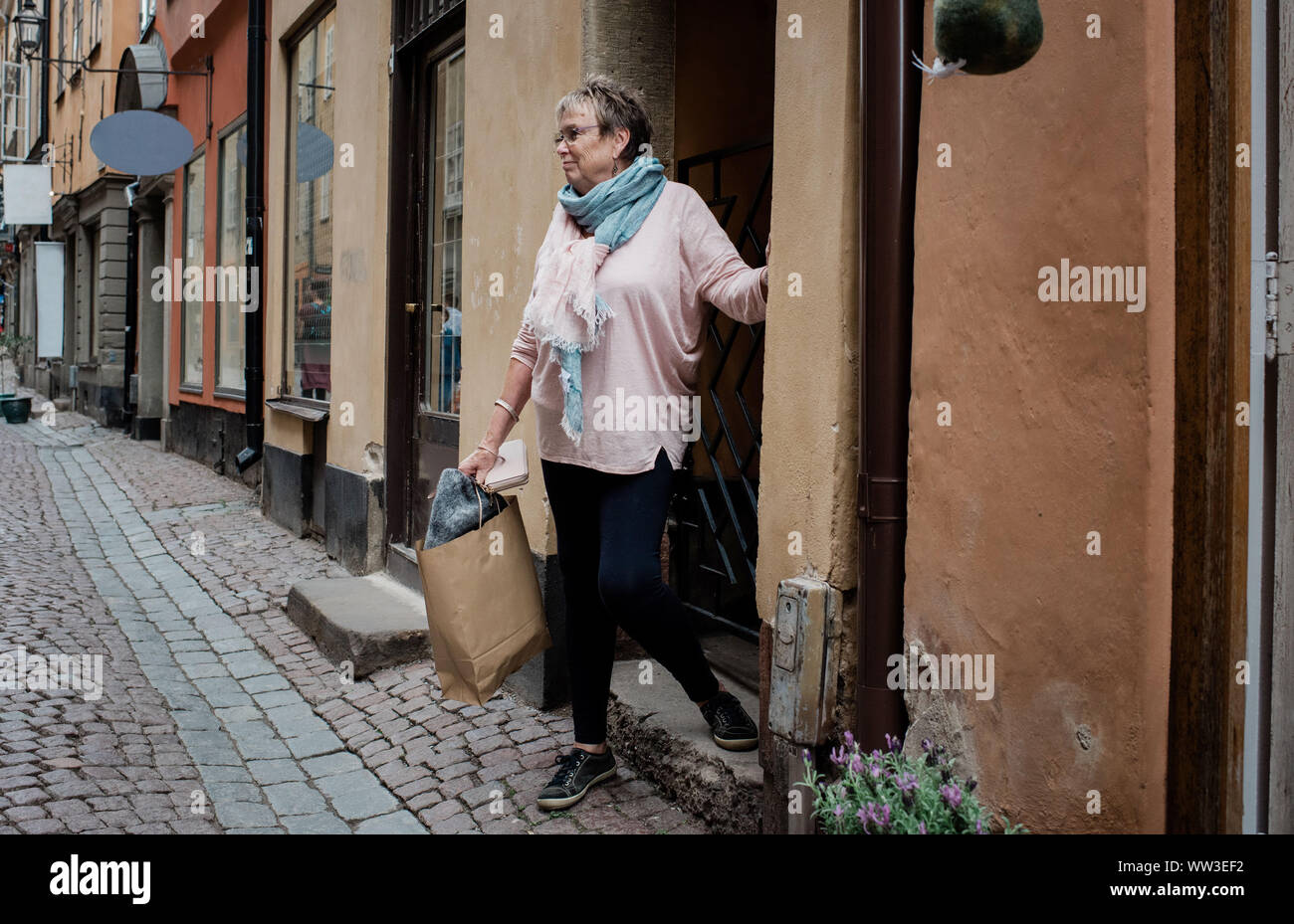 Donna anziana a piedi di una strada a ciottoli shop in Europa viaggiando Foto Stock