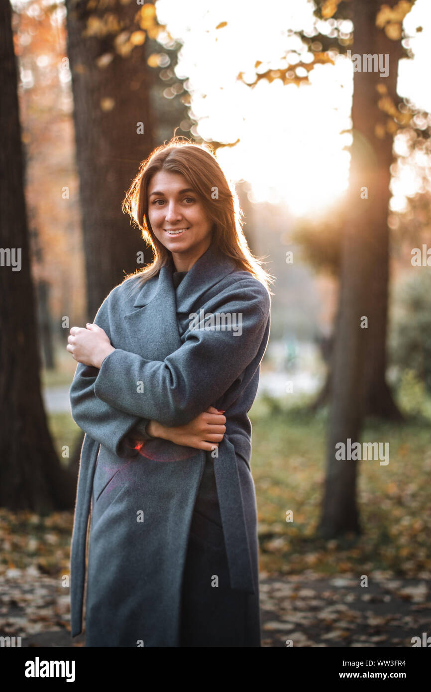 Bella ragazza camminare nel parco d'autunno. Autunno bello e mite clima soleggiato. Giovane donna godendo di caduta. Le donne di moda. Vacanze d'autunno. Persone, autunno e di vita Foto Stock