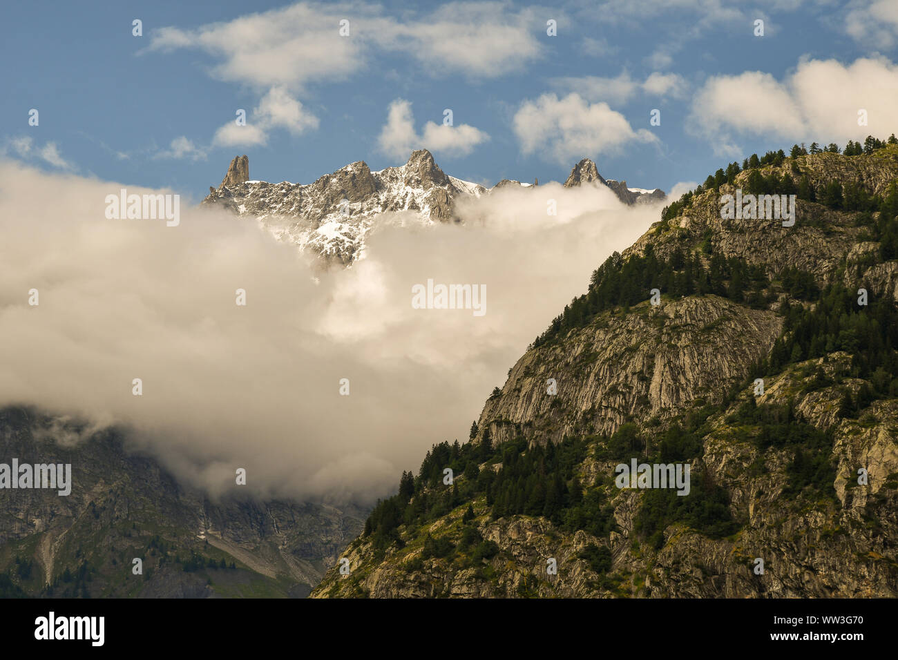 Vista in elevazione della catena montuosa del Monte Bianco con la Dent du Geant picco (il Dente del Gigante) tra le nuvole in estate, Courmayeur, in Valle d'Aosta, Italia Foto Stock