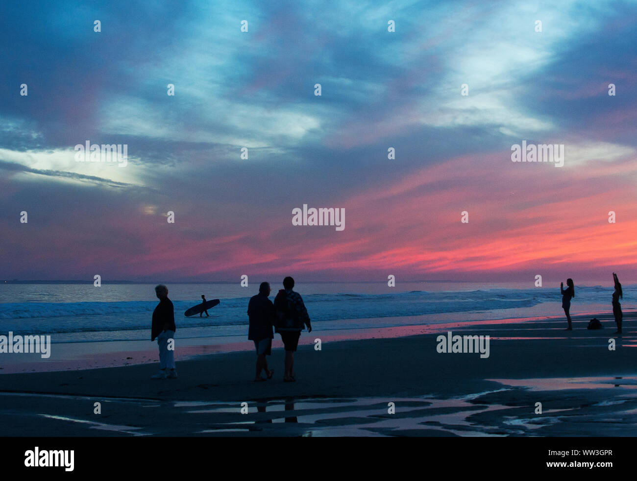 Tramonto colorato litorale con gente camminare sulla spiaggia Foto Stock