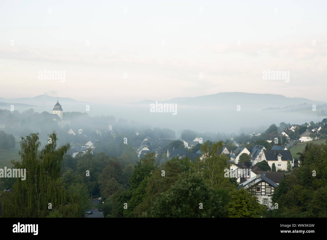 Basso appeso nebbia di mattina oltre la montagna villaggio termale di Grafschaft negli sport invernali regione di Sauerland, Germania con il monastero chiaramente s Foto Stock