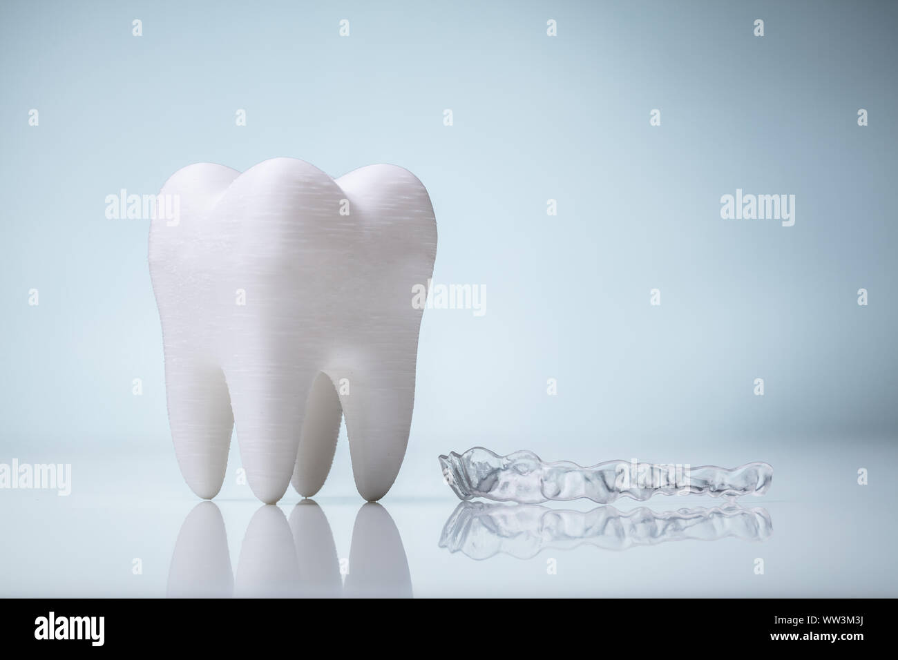 In ceramica bianca Modello di dente e trasparente di protezione bocca sulla scrivania riflettente Foto Stock