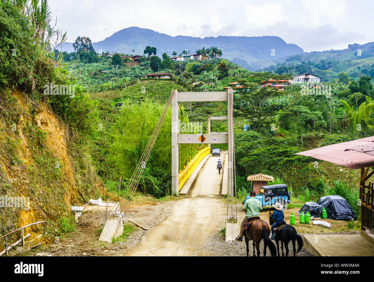 Vista sulla gente facendo trekking a cavallo accanto al ponte di giallo accanto al Jardin in Colombia Foto Stock