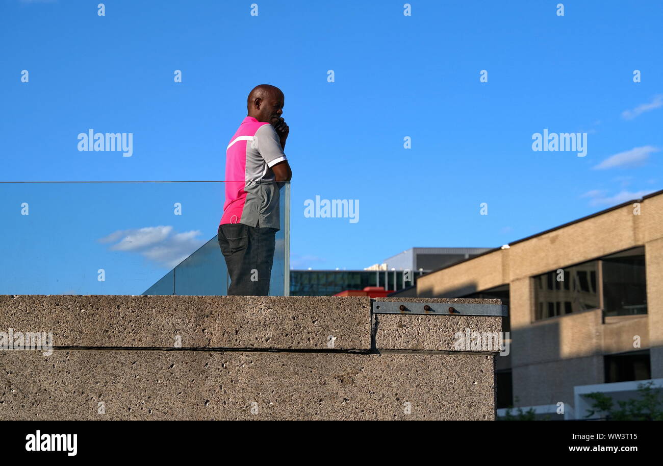 Montreal, Canada. Lug 2019. Un Nero uomo canadese guardando i festeggiamenti in seguito da un edificio sul tetto. Foto Stock