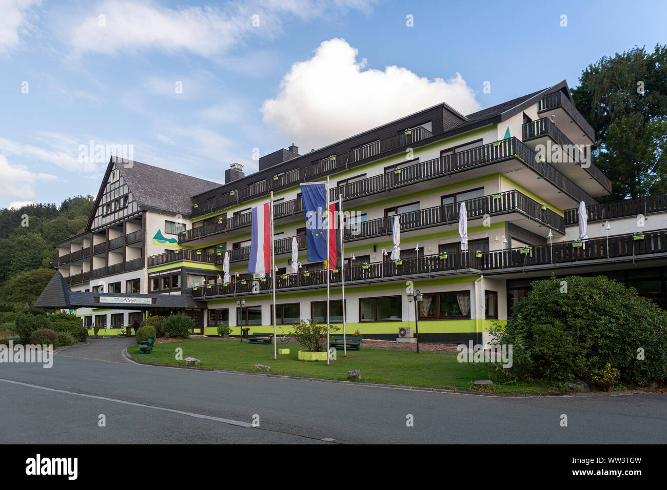 L'Alpin hotel nel centro termale e il Villaggio sciistico di Grafschaft nella regione di Sauerland vicino a Winterberg contro un cielo blu con nuvole Foto Stock