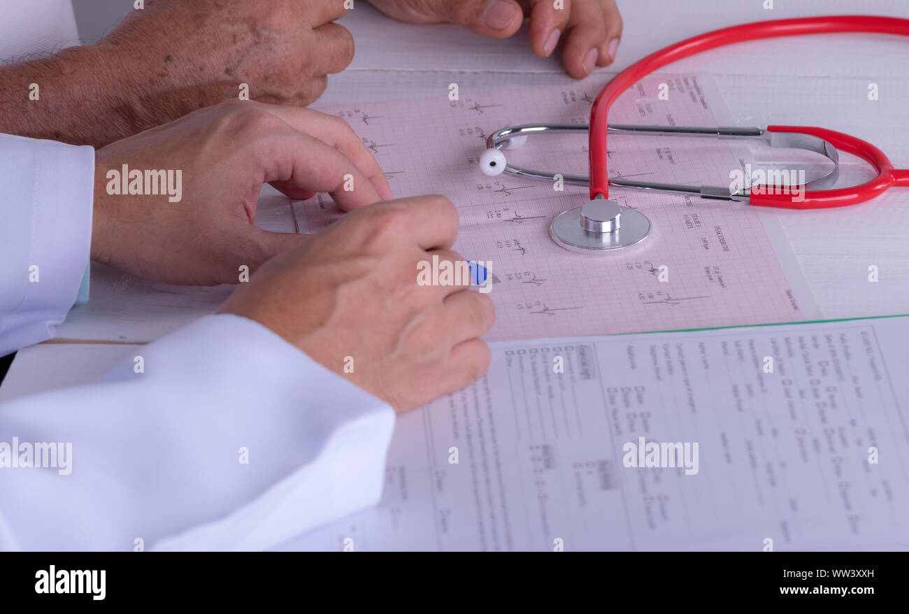 Medico mani con cardiogram grafico con penna. Cardiologo spiegando il suo paziente EKG risultati. Foto Stock