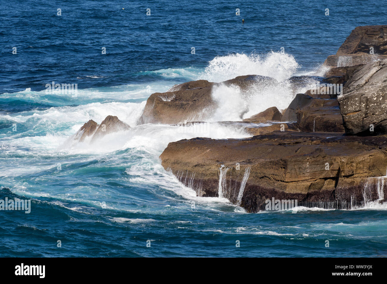 Ocean rigonfiare la rottura su rocce costiere Foto Stock